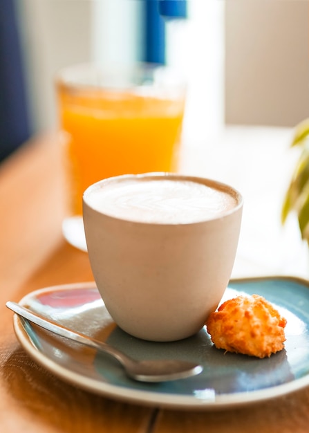 Primo piano del caffè del cappuccino con il biscotto ed il cucchiaio