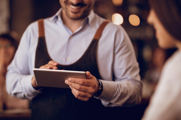 Primo piano del cameriere che prende l'ordine sul touchpad mentre parla con un ospite in un pub