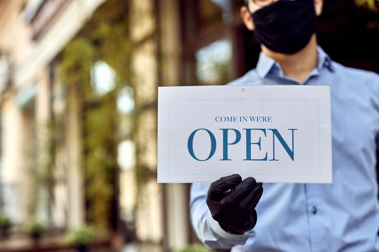 Foto gratuito primo piano del cameriere che tiene il cartello aperto mentre riapre il caffè dopo l'epidemia di coronavirus