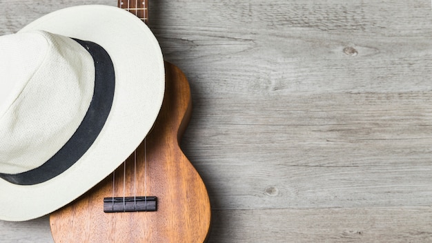 Primo piano del cappello sopra la chitarra contro fondo di legno