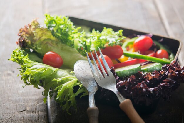 Primo piano del cucchiaio e forchetta con sfondo insalata