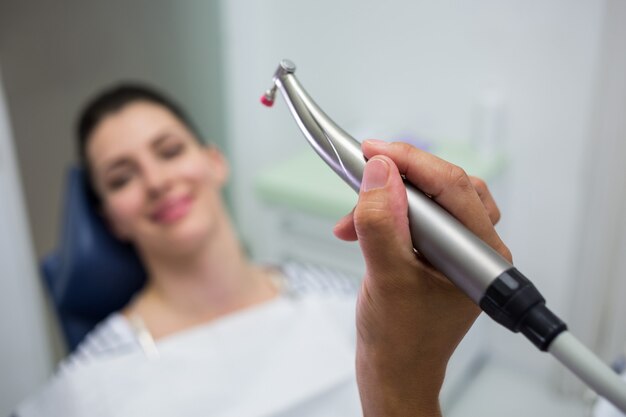 Primo piano del dentista che tiene un odontoiatria, manipolo dentale mentre esaminando una donna