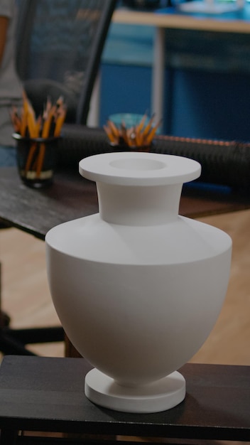 Primo piano del design del vaso sul tavolo per trarre ispirazione nello spazio artistico a casa. Concetto innovativo per la donna nera che crea capolavori sullo sfondo. Giovane artista che usa la matita su tela