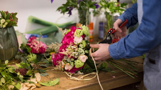 Primo piano del fiorista maschio che crea il mazzo del fiore nel negozio di fiore