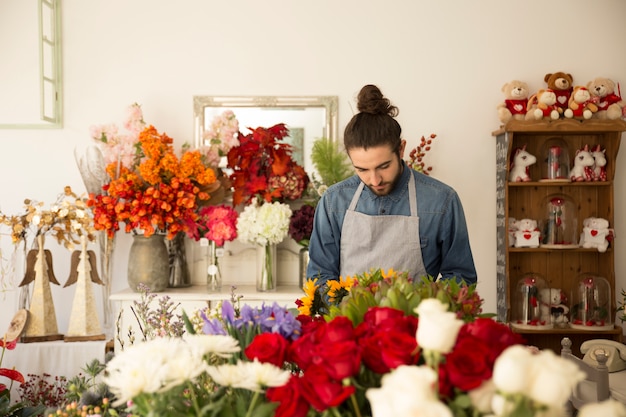 Primo piano del fiorista maschio che lavora nel negozio di fiori colorato