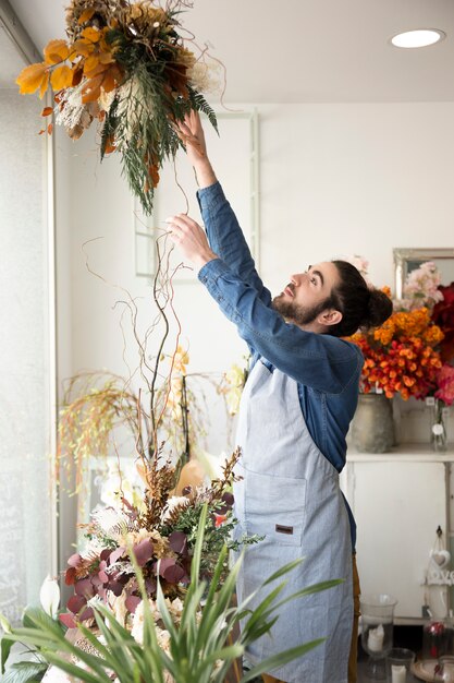 Primo piano del fiorista maschio che sistema il mazzo nel negozio di fiori