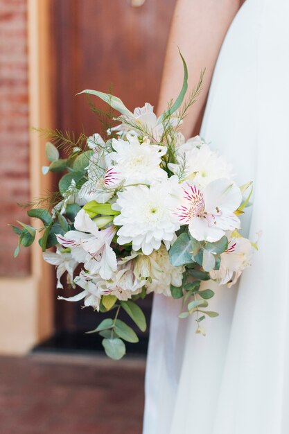 Primo piano del mazzo del fiore della tenuta della mano della sposa a disposizione