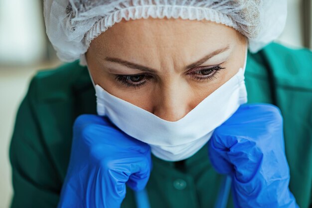 Primo piano del medico femminile sconvolto con la maschera facciale che pensa a qualcosa