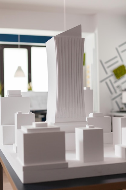 Primo piano del modello in scala architettonica 3D in schiuma bianca del complesso edilizio del grattacielo nell'ufficio moderno dell'architetto. Particolare del progetto di sviluppo urbano sul tavolo di progettazione.