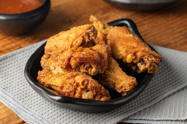 Primo piano del pollo fritto in una ciotola sul tavolo con salsa su di esso