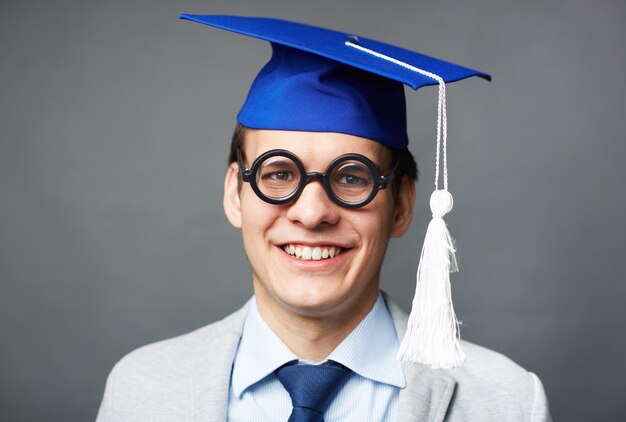 Primo piano del ragazzo intelligente con tappo di laurea