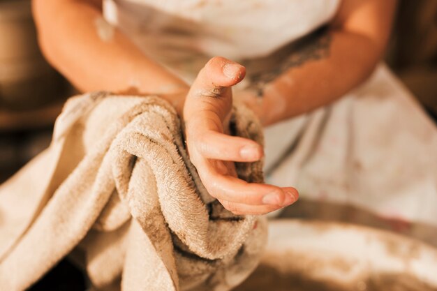 Primo piano del vasaio femminile che pulisce la sua mano con il tovagliolo