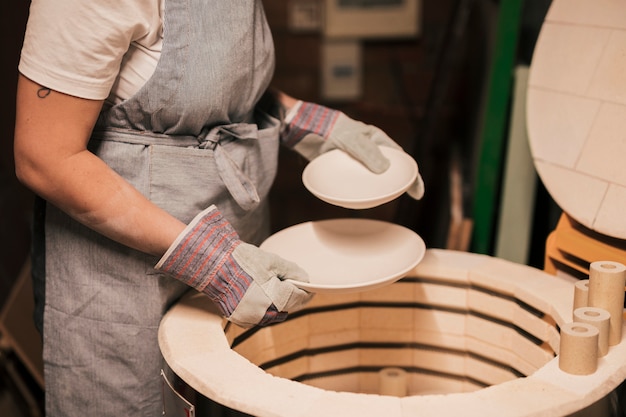 Primo piano del vasaio femminile che sistema i piatti ceramici