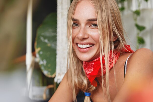 Primo piano del volto di donna bionda attraente soddisfatta con espressione positiva e ampio sorriso