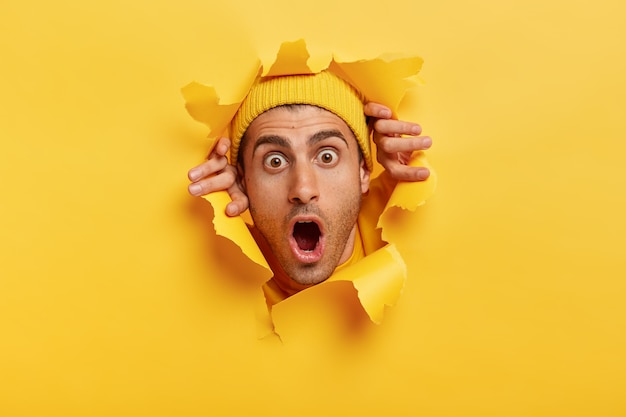 Primo piano del volto di un giovane stupefatto dall'aspetto europeo, indossa un cappello giallo