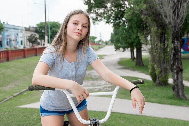 Primo piano dell&#39;adolescente che si siede sulla bicicletta nel parco