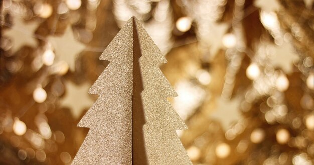 Primo piano dell'albero di Natale in cartone dorato con stelle scintillanti e riflesso lente in calde tonalità dorate