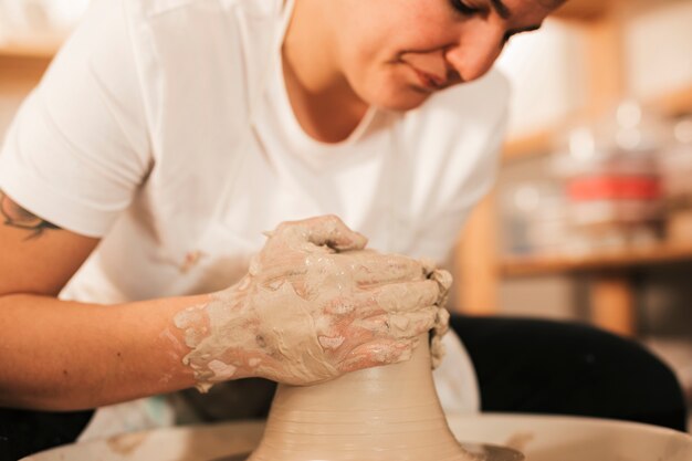 Primo piano dell&#39;artigiano femminile che dà dettaglio all&#39;argilla sulla ruota delle terraglie