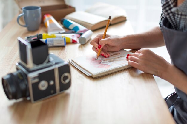 Primo piano dell'artista che lavora allo scrittorio e alla macchina fotografica