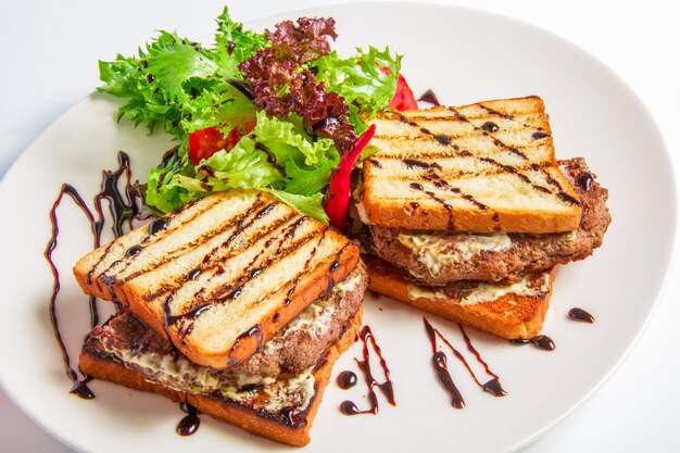 Primo piano dell'hamburger con pancetta e salsa di formaggio, insalata, condimento verde oliva