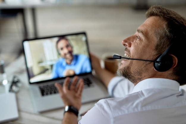 Primo piano dell'imprenditore felice che utilizza il laptop mentre parla online con il suo collega di lavoro