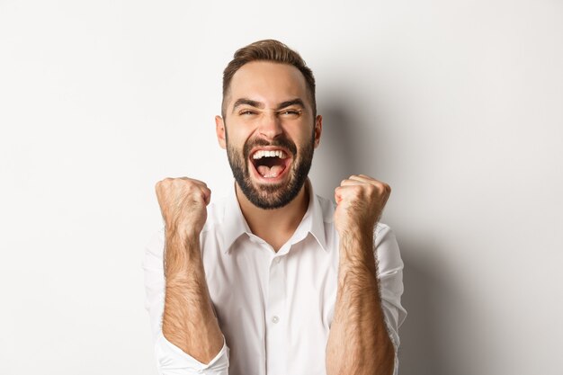 Primo piano dell'uomo caucasico di successo che si rallegra di vincere, fare pompe a pugno e celebrare la vittoria, raggiungere l'obiettivo e gridare di gioia