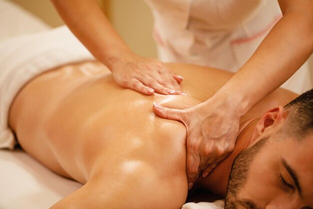 Primo piano dell'uomo che ha massaggio alla schiena durante il trattamento termale al centro benessere