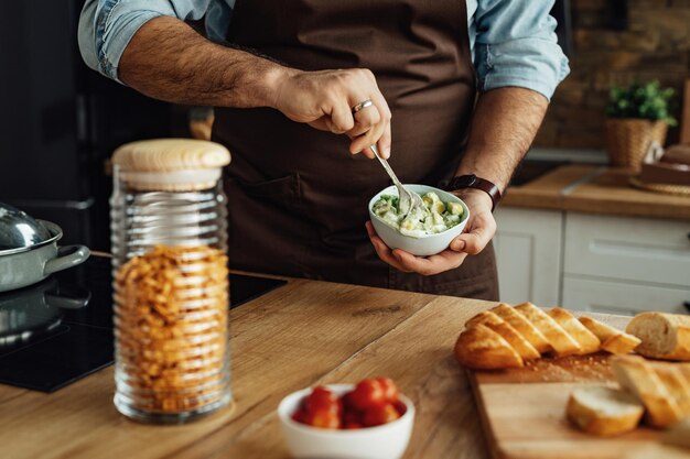 Primo piano dell'uomo che usa l'avocado mentre prepara cibo sano in cucina