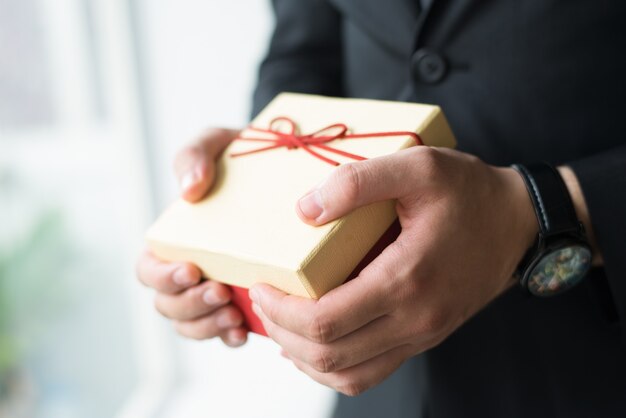 Primo piano dell&#39;uomo d&#39;affari con il contenitore di regalo della tenuta dell&#39;orologio