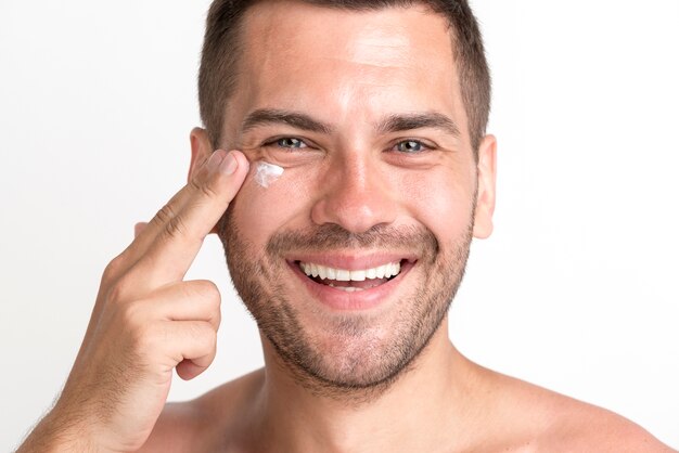 Primo piano dell'uomo sorridente che applica crema sul fronte