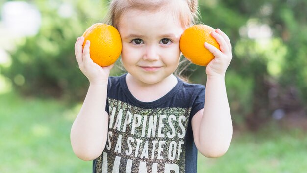 Primo piano della bambina che tiene le arance in mano