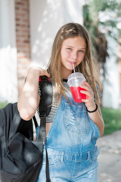 Primo piano della bella ragazza sorridente che beve succo