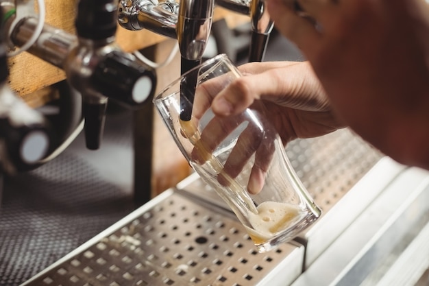 Primo piano della birra di riempimento tenera della barra dalla pompa della barra