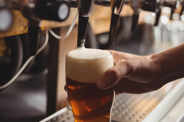 Primo piano della birra di riempimento tenera della barra dalla pompa della barra