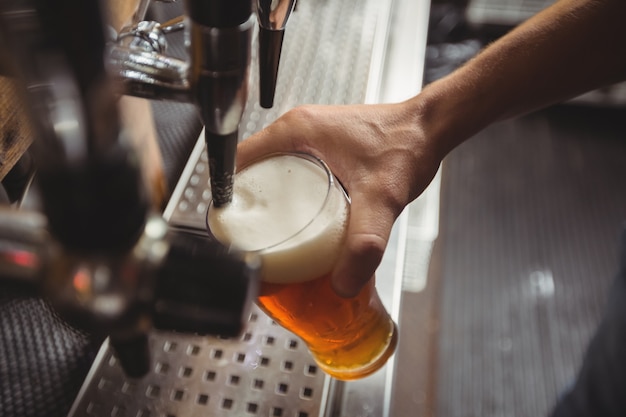 Primo piano della birra di riempimento tenera della barra dalla pompa della barra