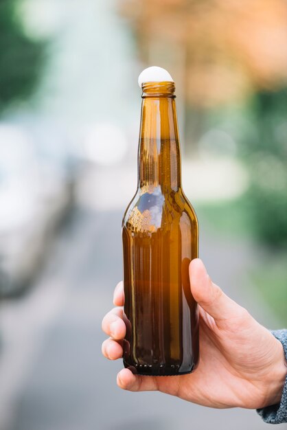 Primo piano della bottiglia di birra della holding della mano di una persona