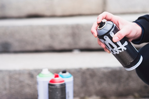 Primo piano della bottiglia di spruzzo dei graffiti della tenuta della mano di un uomo