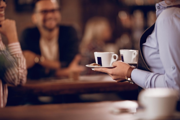 Primo piano della cameriera che trasporta tazze di caffè mentre lavora in un caffè