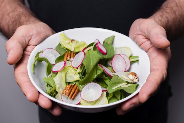 Primo piano della ciotola della holding dell'uomo di insalata in mani