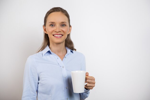 Primo piano della donna attraente positiva che mangiano caffè