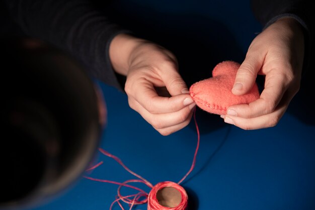 Primo piano della donna che cuce il cuore della peluche