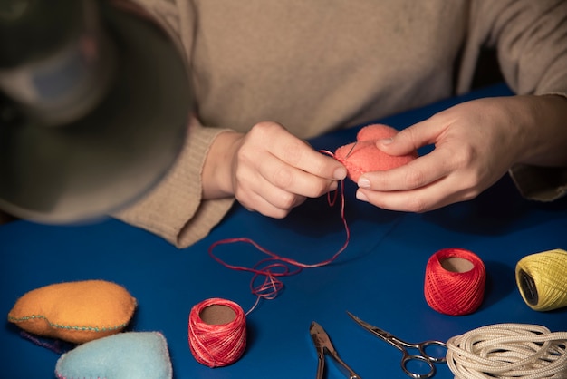 Primo piano della donna che cuce il cuore della peluche