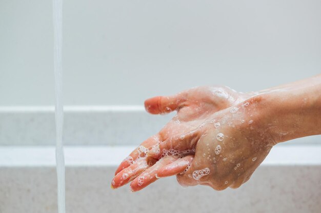 Primo piano della donna che sfrega le mani con un sapone sotto il lavandino del bagno