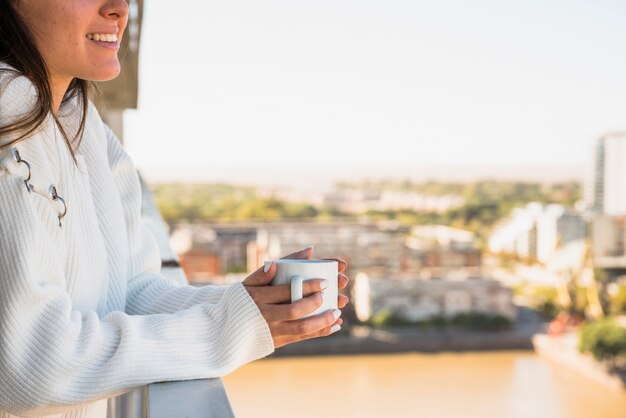 Primo piano della donna che sta in balcone con la tazza di caffè