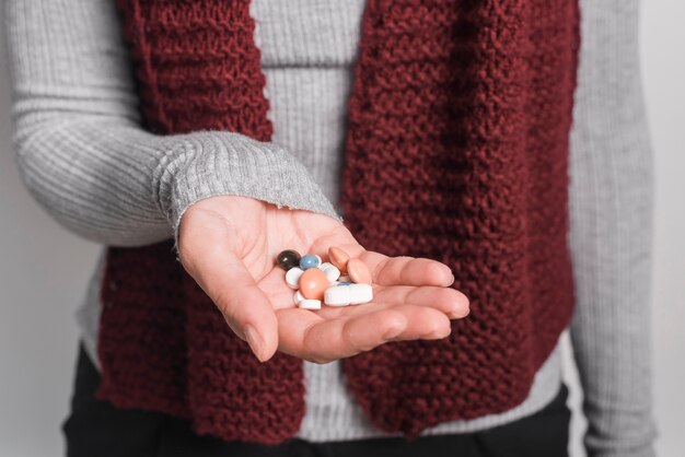 Primo piano della donna che tiene molte pillole in mano