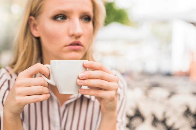 Primo piano della donna che tiene tazza di caffè bianco