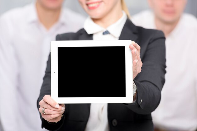 Primo piano della donna di affari che mostra compressa digitale dello schermo in bianco verso la macchina fotografica