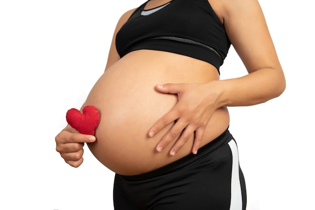 Primo piano della donna incinta che tiene il segno del cuore sulla pancia