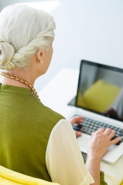 Primo piano della donna maggiore che digita sul computer portatile