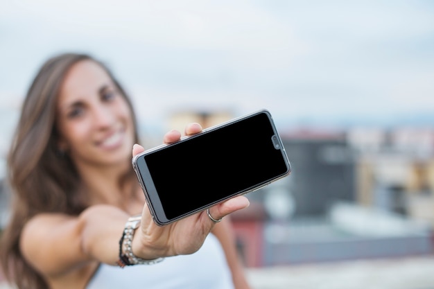 Primo piano della giovane donna che mostra lo schermo dello smartphone